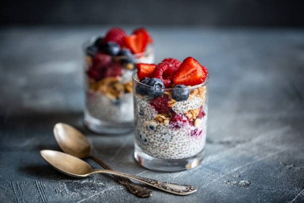 Healthy dessert with chia seeds, blueberries, strawberries, raspberries and granola. Horizontal. Healthy vanilla chia pudding in glass with fresh berries on vintage concrete table. Copy space. Banner. chia seed stock pictures, royalty-free photos & images
