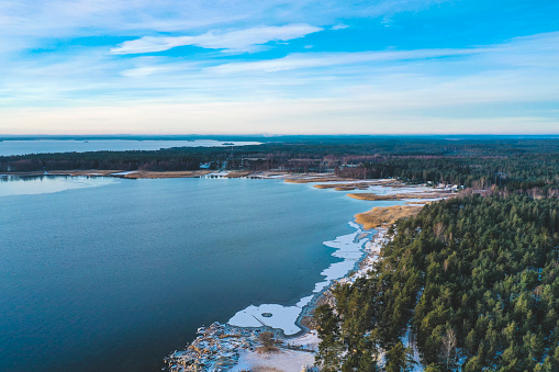 Winter landscape from above showing a nearly frozen lake and a snowy green forest landscape in the city of Karlstad, Sweden.