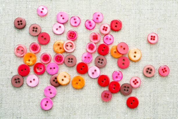 un sacco di bottoni colorati cuciti di diversi colori su un lino tessuti naturali leggeri - plastic hole heap close up foto e immagini stock