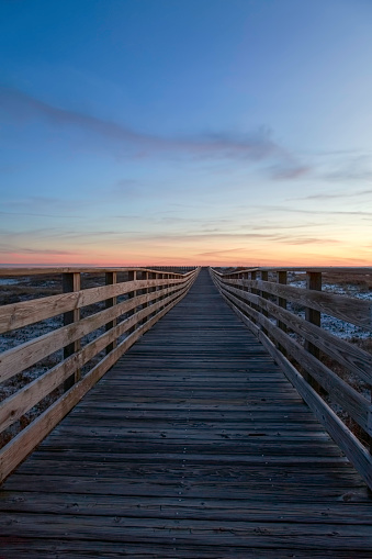 a wooden walkway seems to extend to infinity as the sun sets on a beautiful Alabama beach