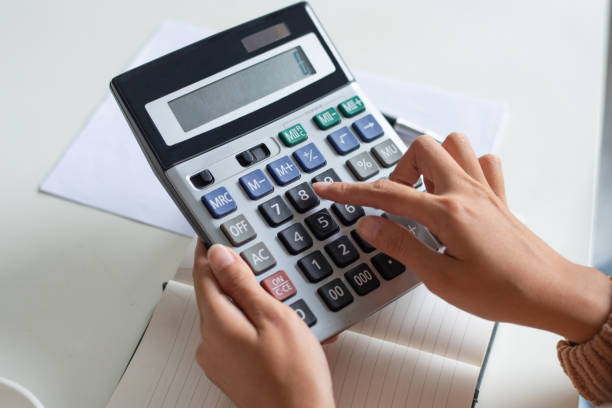 istock Close-up of accountant using calculator while examining report 1092004604