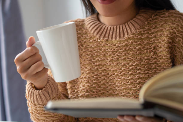 istock Close-up of woman drinking coffee and reading book 1092004648