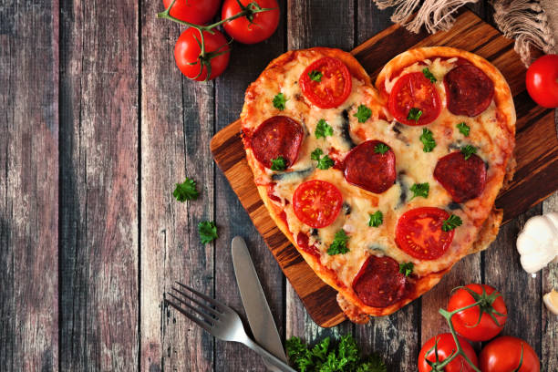 istock Heart shaped pizza for Valentines Day over dark wood, above view, side border table scene 1092007300