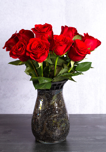 A Dozen Red Roses in a Vase on a Wooden Table