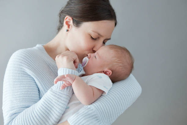 Mother Kissing her Newborn Baby Boy stock photo