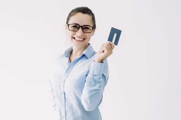 Positive female cardholder happy to receive cash back. Young Caucasian woman in formal shirt raising hand with empty plastic card and posing. Money, benefit concept