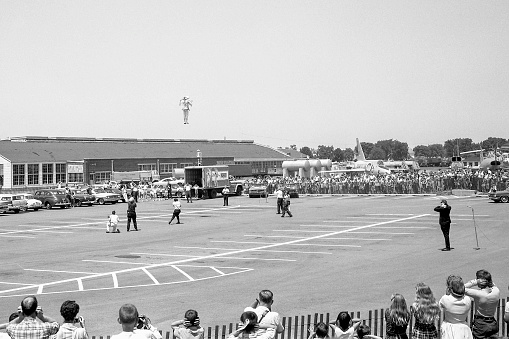 Dayton, Ohio, USA - 1965: Demonstration of Bell Rocket Belt (jet pack) at Wright-Patterson Air Force Base with news crews, spectators and announcer. Scanned film with grain.