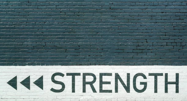 gray brick wall vith strength motto stock photo