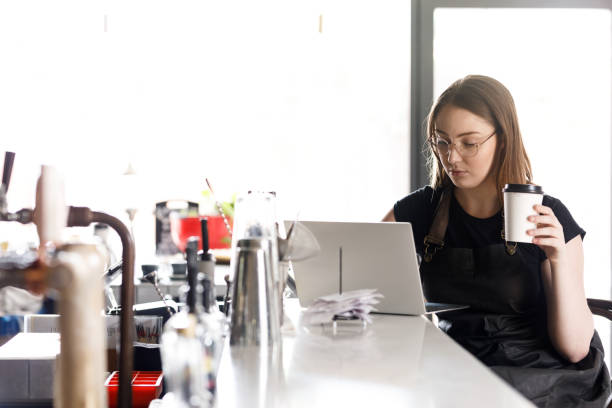istock Young Female Cafe Owner Working On Laptop Doing Accounts 1092037178