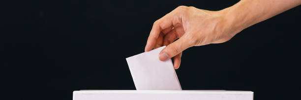 istock Close-up of human hand casting and inserting a vote and choosing and making a decision what he wants in polling box - politics and democracy concept 1092049134