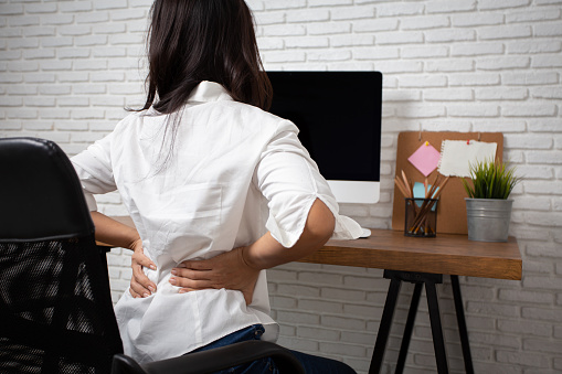 Business woman suffering from back pain in office home