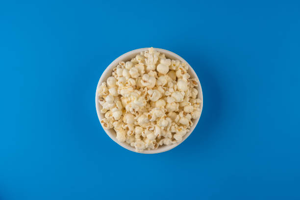 Popcorn viewed from above on blue background Popcorn, Snack, Food, Corn, Food and Drink popcorn snack bowl isolated stock pictures, royalty-free photos & images