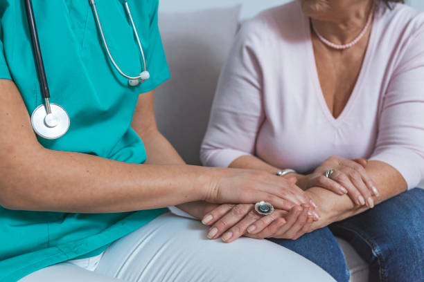 Caregiver in the nursing home Old people in geriatric hospice: Doctor visiting an aged patient, holding hands of a senior woman. Concept of comfort and compassion. Caregiver in the nursing home nurse smock stock pictures, royalty-free photos & images