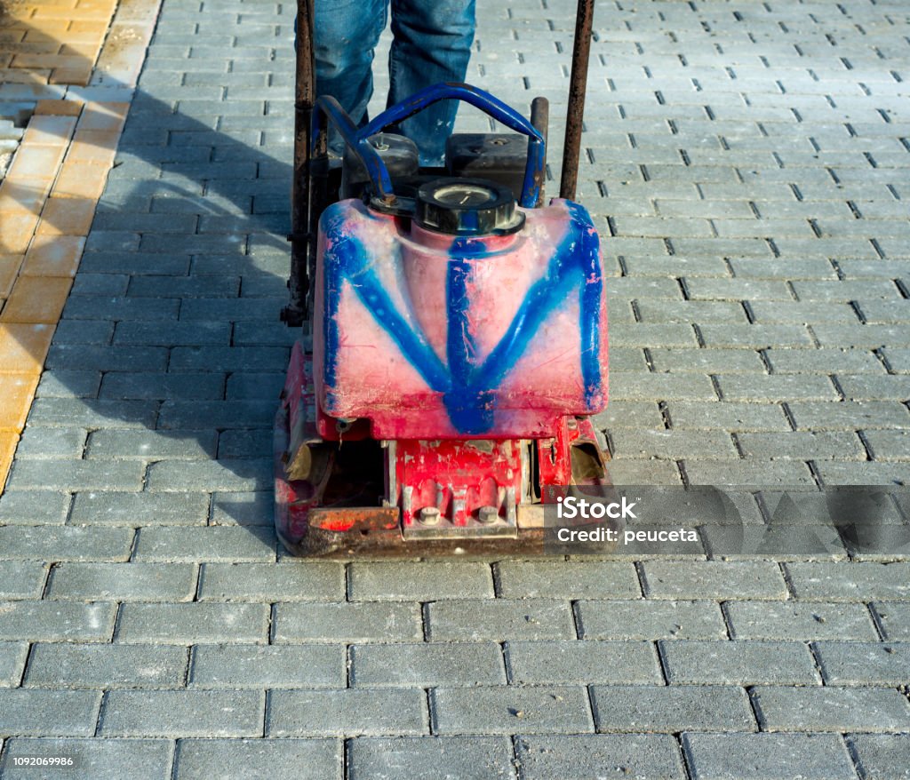 Vibrator with rubber plate for compacting paving with interlocking blocks Architecture Stock Photo
