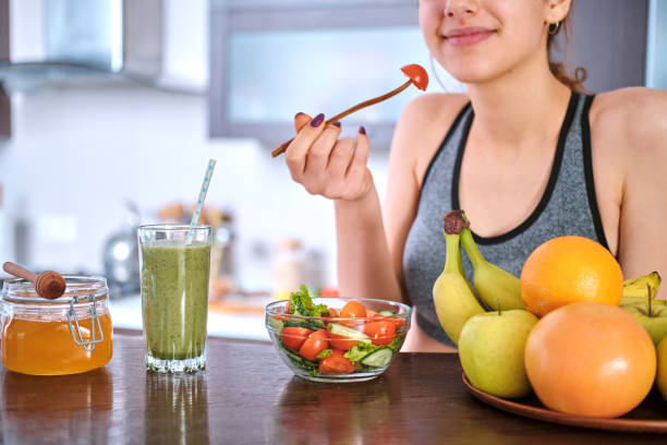 istock Young woman eating salad on the home kitchen after a workout. 1092076122