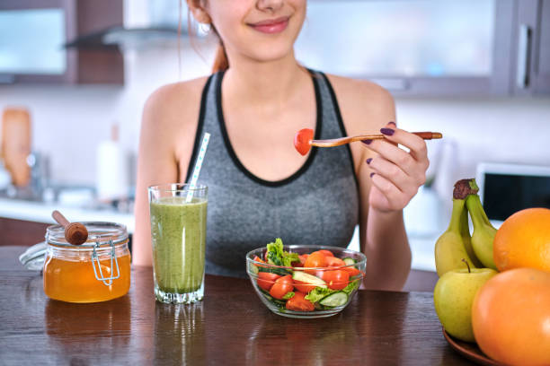 istock Young woman eating salad on the home kitchen after a workout. 1092076162