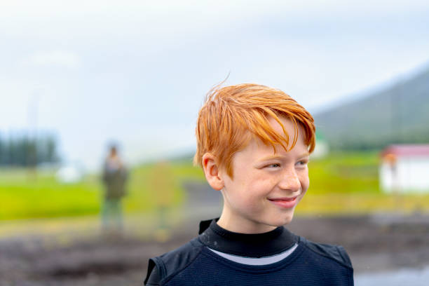 Close-up of smiling boy looking away. Redhead male is contemplating while enjoying nature. He is wearing wetsuit.