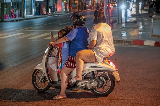 Thanon Patpong, Bangkok, Thailand - December 13, 2018: Two adults and two kids on a motorbike  in the street at the night market, which are biggest and the most famous in Bangkok