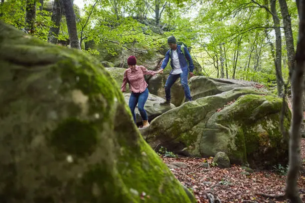 Photo of Mid adult couple hiking on boulders in forest