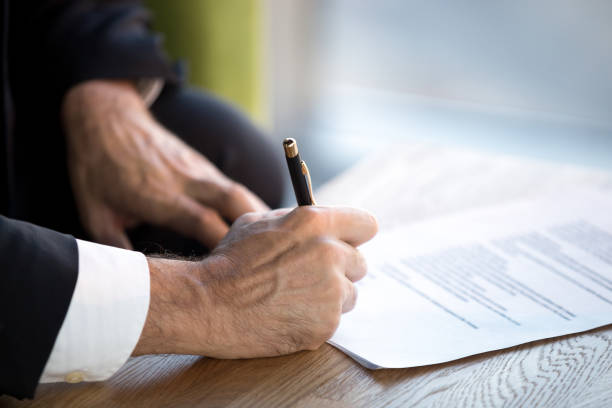 istock Close up male hands puts his signature on official document 1092087558