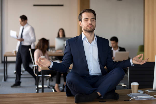 istock Businessman in suit sitting on table and meditating in office 1092087676