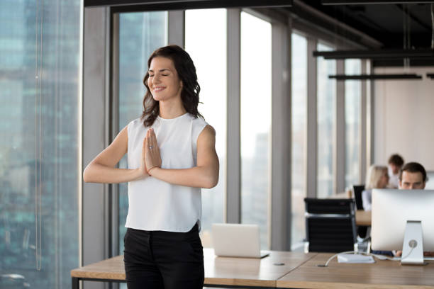 勤務時間中のオフィスのコワーキングでヨガ立ってやって正社員 - zen like meditating yoga business ストックフォトと画像