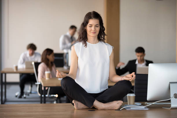 barfuß mitarbeiter meditation sitzen im lotussitz auf bürotisch - zen like meditating yoga business stock-fotos und bilder