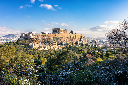 The Parthenon Temple of the Acropolis of Athens, Greece, over the old town Plaka covered in light snow during winter time