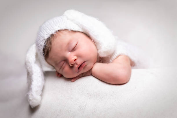 istock Sleeping newborn baby with a bunny hat on a white blanket 1092094466