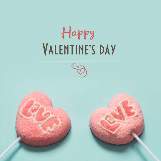 lollipops pink candy on stick with love text on blue . valentine's card. - heart shape snack dessert symbol imagens e fotografias de stock