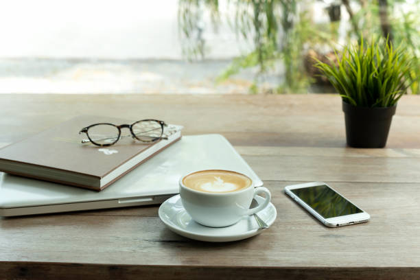 istock Coffee cup and cell phone and laptop computer with glasses on wooden table. 1092097528