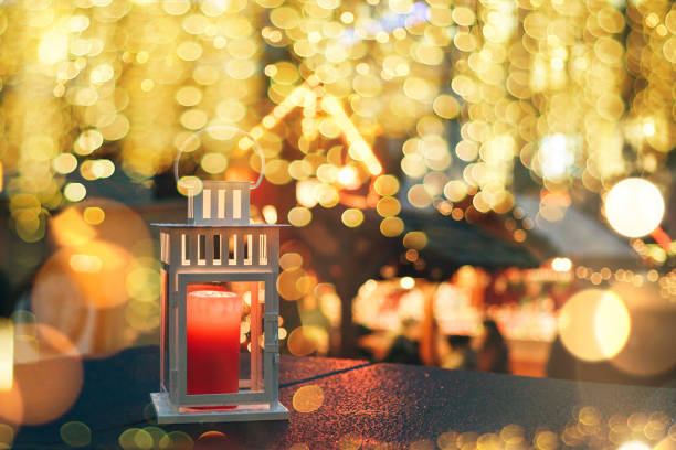 A lamp with a candle at night is decorated with Christmas lights in the background. Festive background.