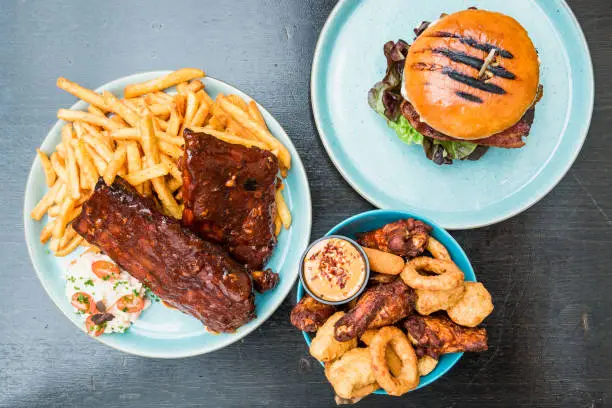 Juicy american spare ribs and steak with bbq sauce cheese, grilled ground meat, toppings, french fries, sweet potato fries, mayo, ketchup, sides.