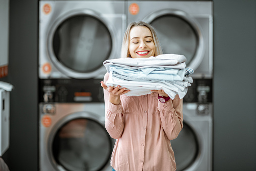 Woman with ironed clothes in the laundry