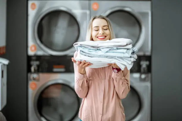 Photo of Woman with ironed clothes in the laundry