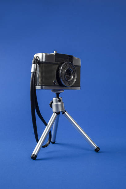 istock Retro style photo camera on tripod against blue background 1092104354