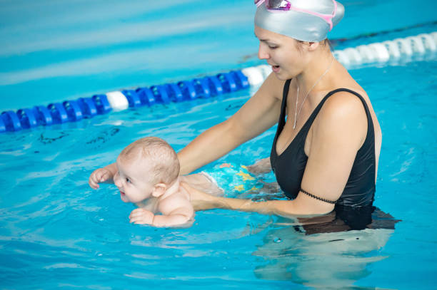 madre enseña a su bebé, cómo nadar en una piscina - bebe bañandose fotografías e imágenes de stock