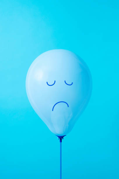 blue balloon with a sad face closeup of a blue balloon with a sad face drawn in it, on a blue background, with some blank space on top january in spanish stock pictures, royalty-free photos & images