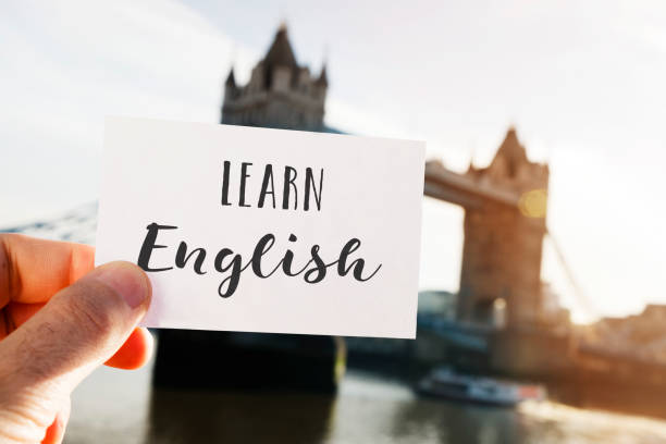 text learn English in London, UK closeup of a young caucasian man holding a signboard with the text learn English written in it, in front of the Tower Bridge in London, United Kingdom england stock pictures, royalty-free photos & images