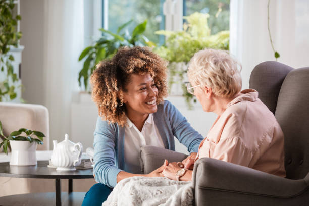 freundliche krankenschwester unterstützt eine ältere dame - seniors stock-fotos und bilder