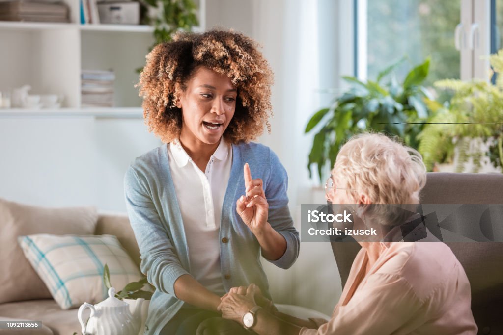 Home nurse talking with an eldery lady Senior woman sitting in armchair in her room and listening to advices given by female home caregiver . Displeased Stock Photo