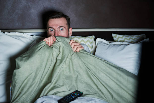 homme, regarder des films d’horreur dans la nuit de peur - hiding fear men peeking photos et images de collection