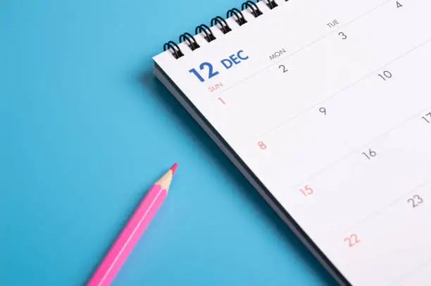 red pencil and calendar on blue background