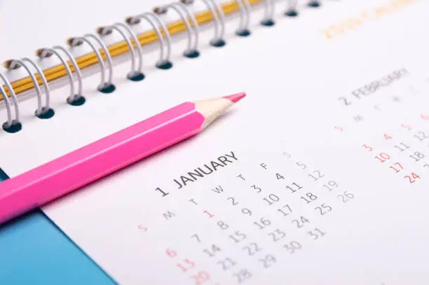 red pencil and calendar on blue background