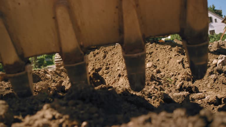 SLO MO excavator bucket digging into the soil at the sunny construction site