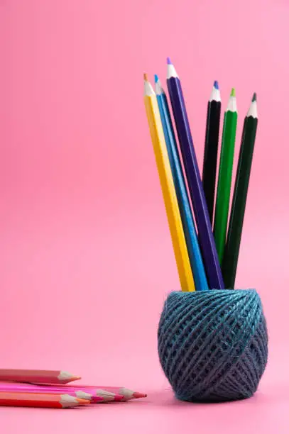 color pencils and string basket on red background