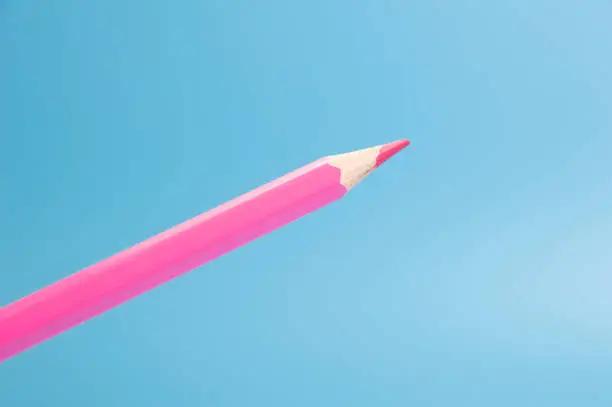 red or pink color pencil floating front blue background