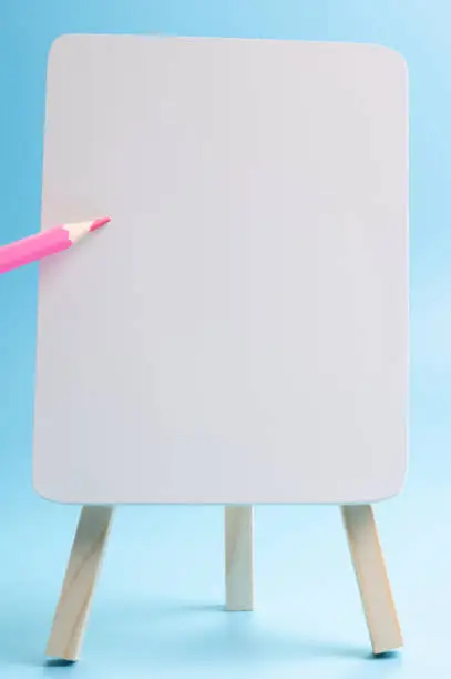 red color pencil floating white easel front blue background