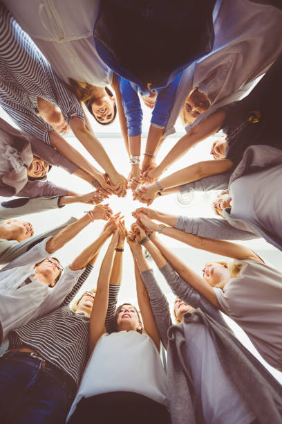Team of women holding hands Low angle view of women standing in a circle holding hands. Trust and team work concept. Unity stock pictures, royalty-free photos & images