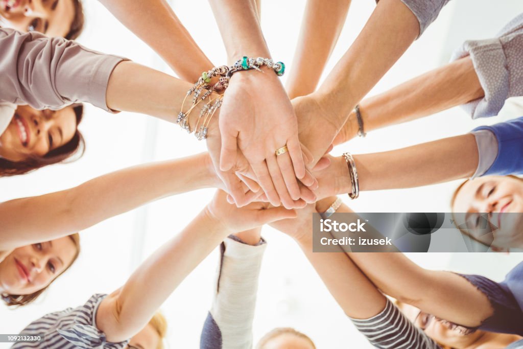 Unity and cooperation Low angle view of women making a pile of hands. Group of female with stack of hands. Community Stock Photo Unity and cooperation Low angle view of women making a pile of hands. Group of female with stack of hands. Community Stock Photo